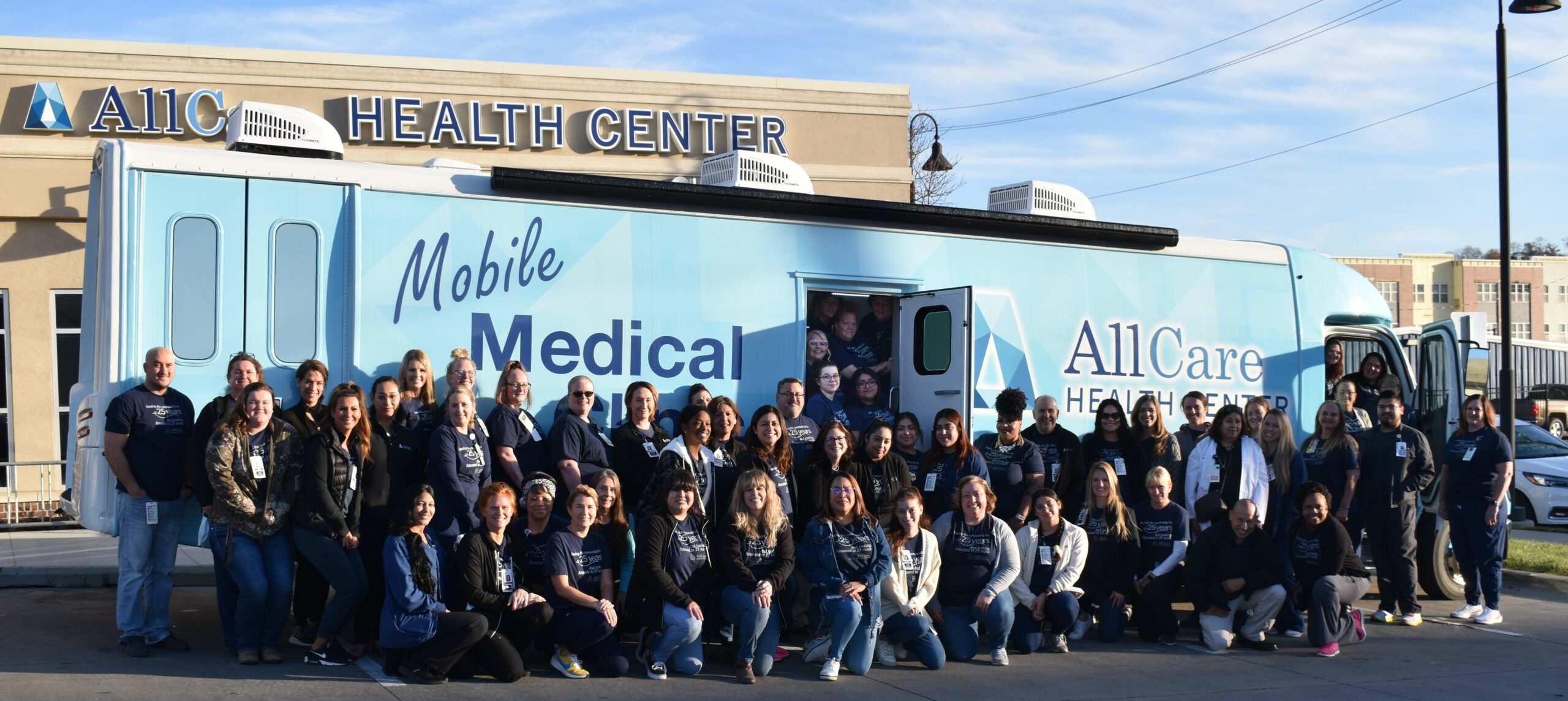 All Care staff pose to take a picture in front of the mobile medical clinic.